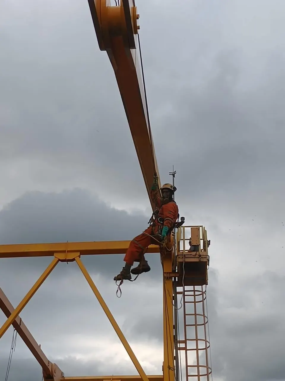 Operador sobre a lança de um equipamento portuário contra o céu